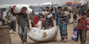 SANLIURFA, TURKEY - OCTOBER 02:  Refugees carry some belongings while crossing the border from Syria into Turkey on October 2, 2014 near Suruc, Turkey. The Turkish Parliament is considering measures that would allow the Turkish military to send ground troops into northern Syria and also allow foreign forces to use airbases on Turkish soil in the ongoing international war against the Islamic State (also called ISIS, or ISIL). Meanwhile ISIS fighters have reached the outskirts of the Kurdish Syrian town of Kobani, which lies just across the border from Suruc.  (Photo by Carsten Koall/Getty Images)